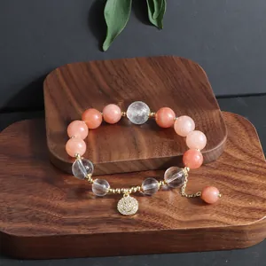 Detailansicht eines Perlenarmbandes mit pfirsichfarbenen Steinen und Smiley-Anhänger