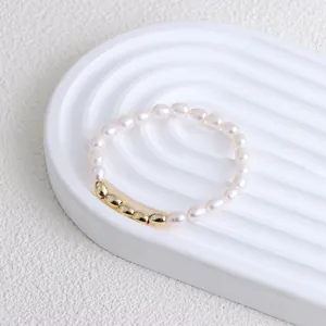 Close-up of minimalist freshwater pearl bracelet with five golden oval beads on display