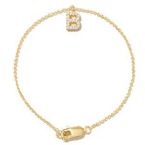Detailed view of gold chain bracelet with zircon-encrusted letter B pendant