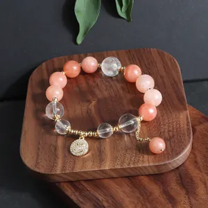 Detailansicht des pinkfarbenen Sonnenstein Armbands mit goldenem Smiley Anhänger