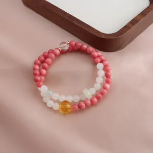 Detailed view of a double-strand pink and white beaded bracelet with a yellow citrine accent