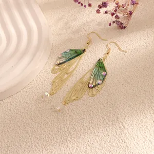 Detailed macro view of green gradient cicada wing earrings with gold filigree and crystals.