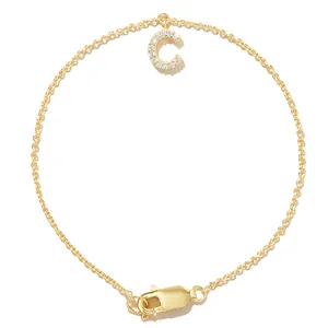 Close-up of gold chain bracelet featuring a shimmering zircon-studded initial 'C' charm.