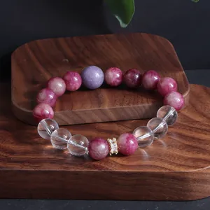 Nahaufnahme eines handgefertigten Perlenarmbands mit rosa Turmalin und Bergkristall auf Holz