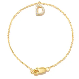 Detail view of a gold chain bracelet with a sparkling zircon-inlaid letter D charm.