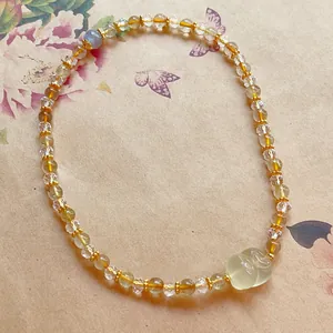 Detail view of natural citrine bracelet featuring a carved cat charm and moonstone.