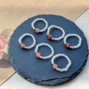 Nahaufnahme von elastischen Ringen aus Erdbeerquarz und Kristallperlen auf Schiefer