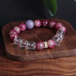 Detailansicht eines eleganten Kristallarmbands mit rosa und klaren Quarzperlen auf Holz
