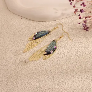 Close-up detail of elegant iridescent cicada wing dangle earrings with gold metal finish.