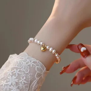 Gros plan d'un élégant bracelet en perles d'eau douce avec un pendentif cœur doré.