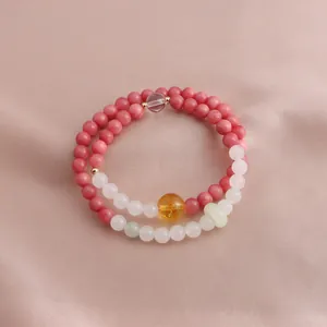 Detail view of double-layer beaded bracelet with pink stones and yellow crystal accent