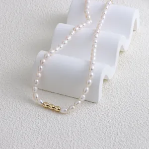 Detail shot of elegant freshwater pearl necklace featuring three golden beads on a white stand