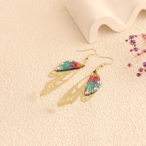 Detailed view of colorful iridescent cicada wing earrings with gold openwork design