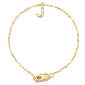 Detailed view of gold chain bracelet featuring a shimmering zircon-inlaid letter J charm