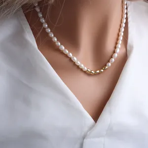 Detailed view of elegant freshwater pearl necklace with central gold beads on white shirt