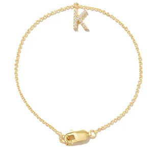 Macro view of a delicate gold chain bracelet with a sparkling zircon-encrusted letter K charm.