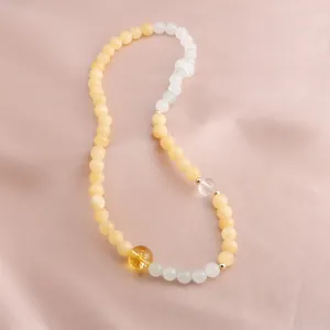 Close-up detail of Citrine and Gold Silk Jade beaded bracelet laid on elegant pink silk fabric