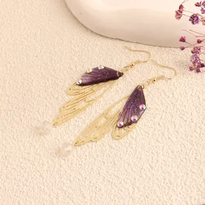 Close-up detail of elegant purple and gold cicada wing drop earrings with crystal accents