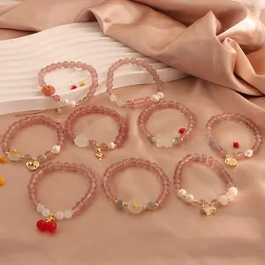 Detailed view of various natural strawberry crystal bracelets with pearls and charms