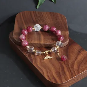 Detailansicht eines Kristallarmbandes mit rosa Turmalin und goldenem Fischschwanz