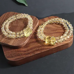 Detailed view of two natural citrine bead bracelets with charms on wooden display.
