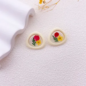 Primer plano de pendientes hechos a mano con flores secas reales de colores.