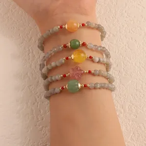 Close-up of stacked moonstone bracelets with colorful agate and pumpkin beads on wrist