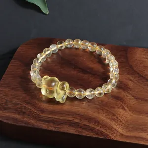 Close-up detail of natural yellow citrine bracelet with carved fox pendant on wood board