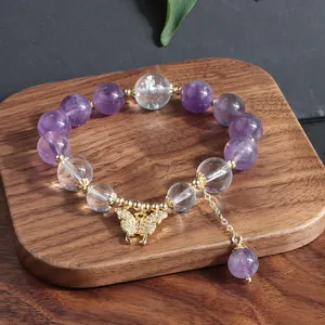 Detailansicht eines Amethyst-Perlenarmbands mit einem funkelnden goldenen Schmetterling