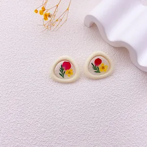 Vista detallada de pendientes de flores secas hechos a mano con pétalos de colores