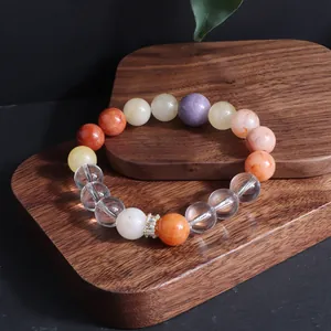 Nahaufnahme eines bunten Edelsteinarmbands mit Sonnenstein und Amethyst auf Holz