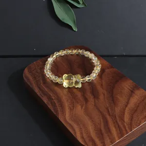 Close-up of a natural yellow citrine beaded bracelet with a carved fox on a wood block.