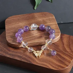 Detaillierte Nahaufnahme des Armbands aus Amethyst- und Quarzperlen mit goldenem Schmetterling