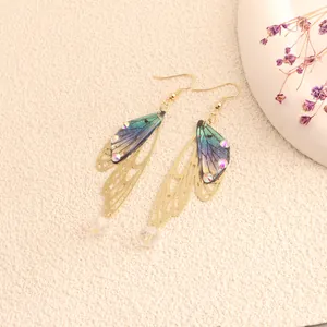 Detailed view of iridescent cicada wing earrings with gold filigree and crystals.