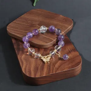 Nahaufnahme von Amethyst- und Quarzkristallarmband mit goldenem Schmetterling
