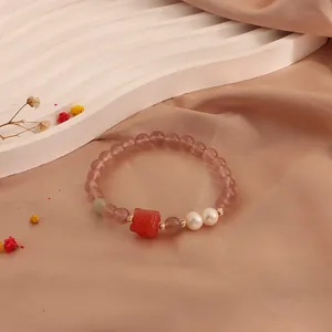Close-up of strawberry quartz bracelet with freshwater pearls and red cat paw bead.