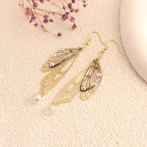 Detailed view of gold butterfly wing earrings with iridescent rhinestones and dried flowers