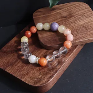 Nahaufnahme eines Naturstein-Armbands mit Sonnenstein und Rosenquarz auf Holz