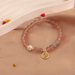 Close-up of strawberry crystal beaded bracelet with freshwater pearl and gold Fu charm