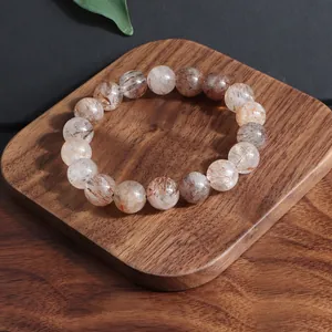 Primer plano de una pulsera de cristal Super Seven natural sobre una base de madera.