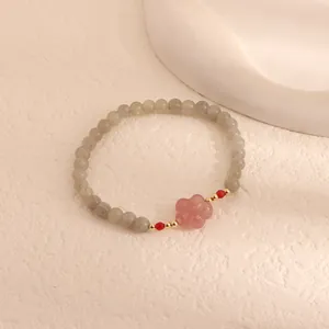 Close-up of elegant moonstone beaded bracelet featuring a pink flower quartz charm