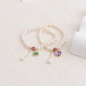 Detail view of two natural freshwater pearl bracelets with heart and fan pendants