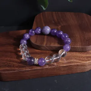Detailaufnahme von Amethyst- und Quarzkristallperlen mit goldenem Abstandshalter auf Holz