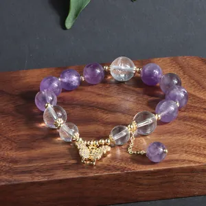 Nahaufnahme von Amethyst- und Quarzarmband mit einem glänzenden Gold-Schmetterling