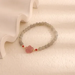 Detail of moonstone and quartz beaded bracelet with a delicate pink flower charm