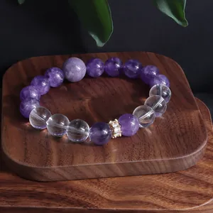 Nahaufnahme eines Perlenarmbands aus Amethyst und klarem Quarz auf einem rustikalen Holztablett