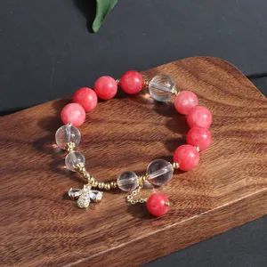 Nahaufnahme eines Perlenarmbandes mit rosa Turmalin, Kristall und goldenem Schmetterling