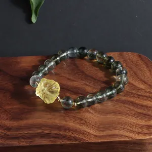 Detail of a green phantom crystal bracelet with a carved lemon yellow lion charm.