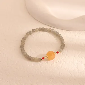 Close-up detail of labradorite bead bracelet featuring a carved orange pumpkin chalcedony bead