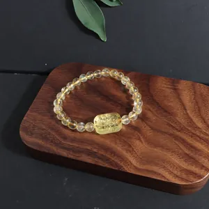Detailed view of a natural citrine fox bracelet on a rustic wooden display base